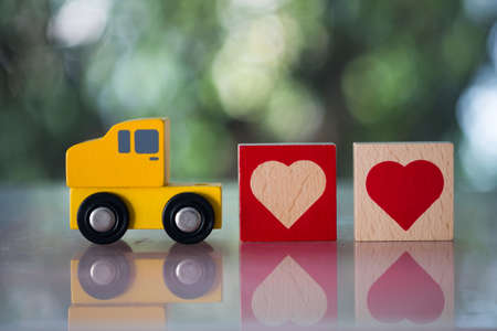 Wood heart follow yellow toy car for sending to couple. The concept of love and Valentine's day