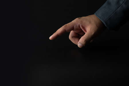 Businessman in suit point on a black background, can put your text at the finger, copy spaceの写真素材