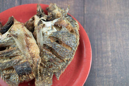 Deep crispy fried Tilapia fish after fried on red dish ready to eat. Concept of Thai style homemade foodの写真素材