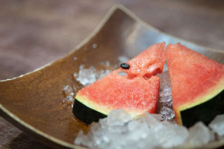 Fresh sliced watermelon served on ice on wood tray