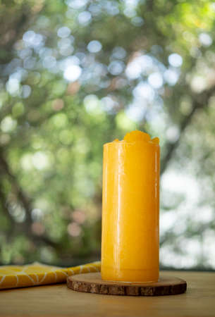 Freshly orange smoothie in tall glass put on wood table on garden backgroundの写真素材