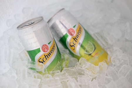 Bangkok, Thailand - February 28, 2021 : Two can aluminium Schweppes manao soda on ice basket, Popular carbonated waters introduced in 1870.のeditorial素材
