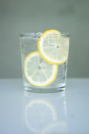 Glasses of water filled with slices of lemons. shadow reflection on table. Selective focus