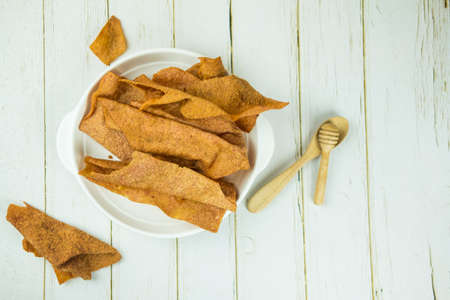 Sliced sheets of dried and crispy pork in white plate. Thai style appetizer.の写真素材