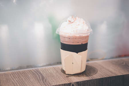 Cup of iced chocolate with whipped cream on wooden tableの写真素材