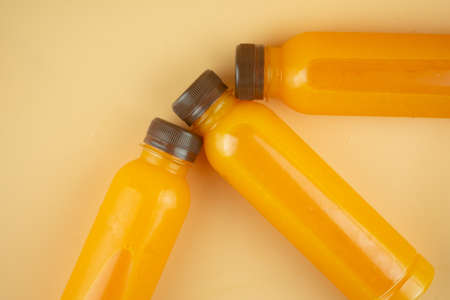 Plastic bottle 100 % fresh orange juice against orange background and copy spaceの写真素材