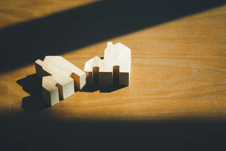 Wooden flat house on wood table with shadow from window. Concept of real estateの写真素材