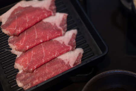 Raw freshly thin beef prepared for hot pot and Japanese sukiyaki served on black tray