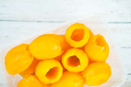 Mayongchid is peeled was seeds removed in a plastic box on wooden background. Characteristics of oval-like eggsの写真素材