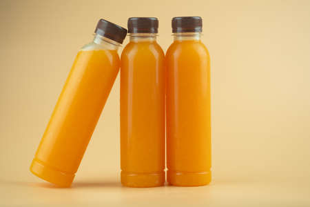 100% pulp organic fresh orange juice are in a bottles with brown cap on a orange background.の写真素材