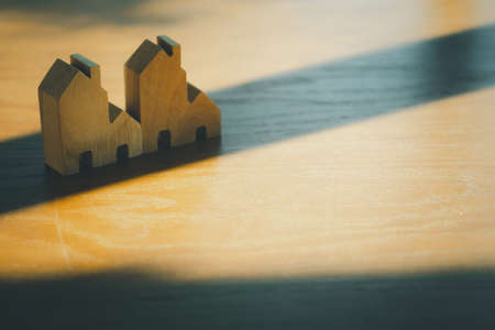 Wooden flat house on wood table with shadow from window. Concept of real estateの写真素材