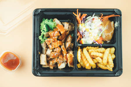 Grilled pork steak with vegetable salad, mashed potatoes and french fries in takeaway box. Top viewの写真素材