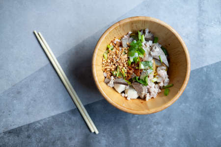 Top view of dry egg noodles, minced pork on a wooden bowl. Thai-Asian food mixing concept