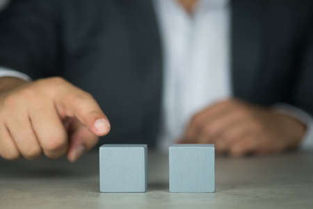 Finger of Businessman in suit touch to wood block on table.の写真素材