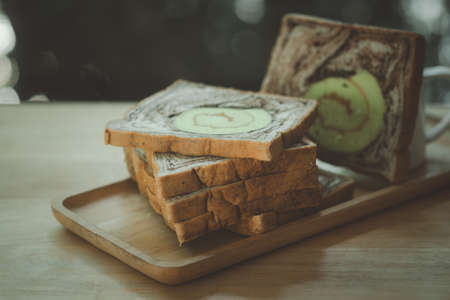 Slice of bread marble chocolate and roll pandan served on wooden tray