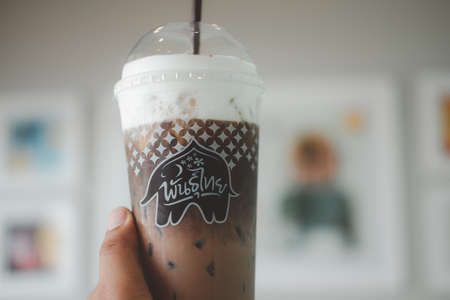 Bangkok - Thailand, April 11, 2021 : Man hand holding plastic glass of iced Mocha coffee at cafe Punthai, PunThai Coffee shop is a famous Thailand franchise open for service in the PT gas station.のeditorial素材