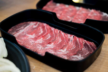 Thin sliced raw beefon black tray for prepare cooking Shabu Shabu