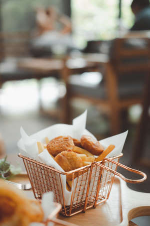 Fried chicken nuggets with french fries in a basket.  Restaurant menu unhealthy snackの写真素材