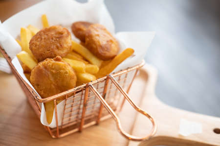 Hot deep fried snacks : crispy chicken nuggets, french fries in basket. Selective focusの写真素材