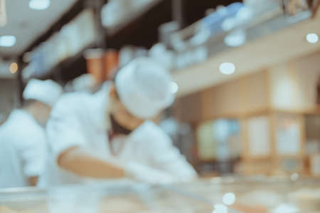 Abstract blur background of sushi restaurant with chef making sushiの写真素材