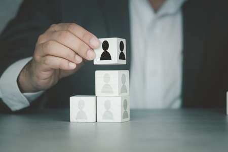 Businessman in suit put wood cube with human symbol. Human resources and team management conceptの写真素材