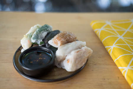 Mix of various steamed dumpling stuffed such as garlic chives, taro and bamboo shoot with sweet sauce in dish, ready to eatの写真素材