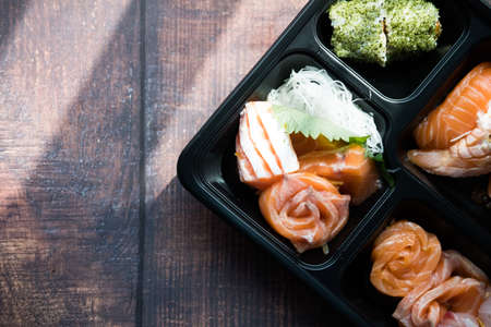 A box of various salmon sashimi placed on wood table. Top view