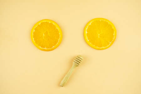 Honey stick and slices of sliced orange on orange background. Top view