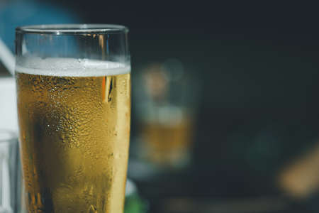 A pilsner style glass filled with beer on a pub backgroundの写真素材