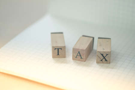 Word of TAX on wooden cubes on grid lines paper. Business and tax concept. Pay taxの写真素材