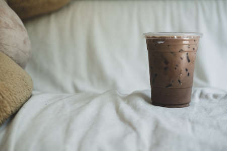 A cup of iced coffee Mocha place on white sofa for relax and refresh in the afternoon.