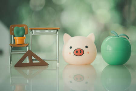 Creative minimalist photo of student desk, green apple and pig doll. The concept of back to schoolの写真素材