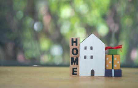 Wood cube block with word âHOMEâ and white wood home with gift box. The concept of new homeの写真素材