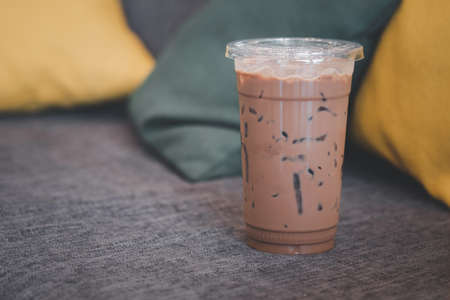 Iced mocha coffee in plastic glass place on gray burlap sofa and pillow.の写真素材