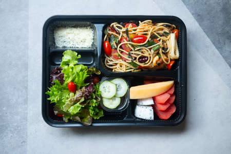 Top view of Stir-fried spicy spaghetti seafood with salad and fruit in set of lunch boxの写真素材