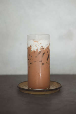 Iced mocha with cream on top in tall glass.