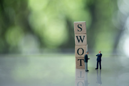 Miniature people businessman standing with letter block in word SWOT (Abbreviation Of Strength, Weakness, Opportunities, Threats)の写真素材