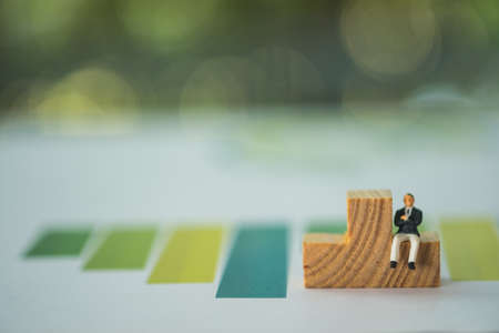 The man sitting on a wooden puzzle pieces and bar chart background. Strategy planning concepts.の写真素材