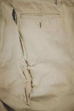 Denim hole in yellow pants, background or textureの写真素材
