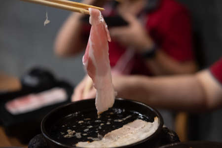 Chopsticks picking up grilled roasted pork slice on korean barbecue