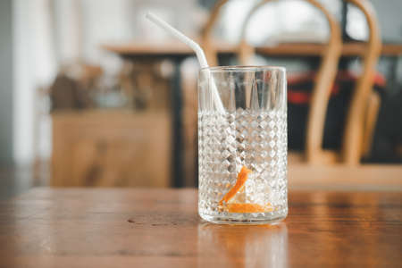 Empty glass of ice and slice orange after drink on wood table at cafeの写真素材