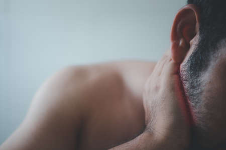 Unhappy bearded man suffering from neck pain at home.の写真素材
