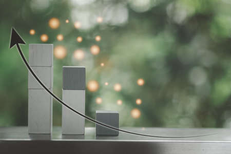 Graph arrow increase and step wood cube, work business process success in positive way on a beautiful nature backgroundの写真素材