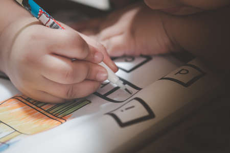 Little boy write to paper with pencil on desk. The concept of practice writingの写真素材