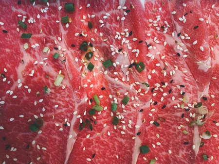 Raw freshly prepared sliced beef sprinkle black sesame seeds and white sesame seeds with sliced spring onions for barbecue (BBQ).Top viewの写真素材