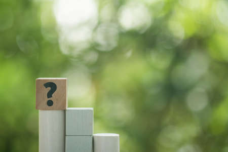 Question mark sign on wood cube on nature background. The concept of support or questionnaireの写真素材