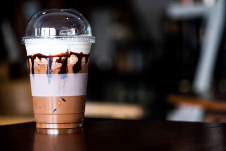 Iced coffee in plastic cup on wooden table at cafe. The best start to any morning in coffee shop...