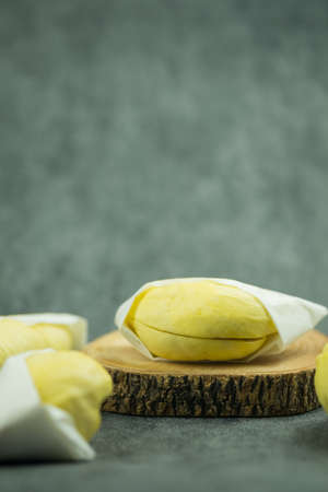 Ripe durian wrapped in paper placed on wood board. Selective focus