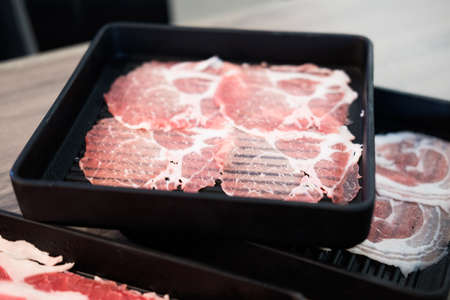 Thin sliced raw beef on black tray prepare for cooking shabu shabuの写真素材