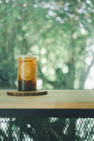 Close up a glass of sparkling soft drink with orange slices on the table in the garden. Refreshing drink.の写真素材